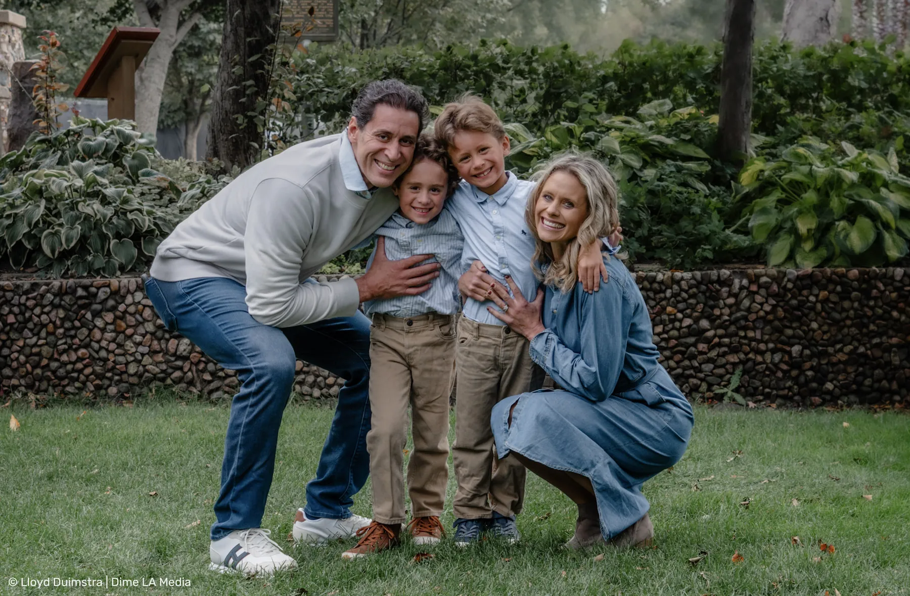 Family huddled in a crouching group hug on the grass