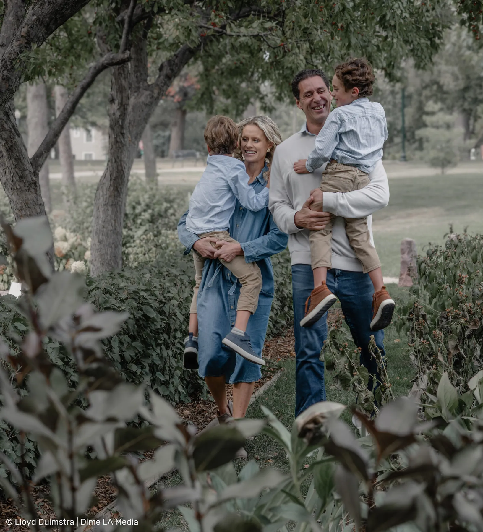 Dad lifting his son high while mom holds his brother