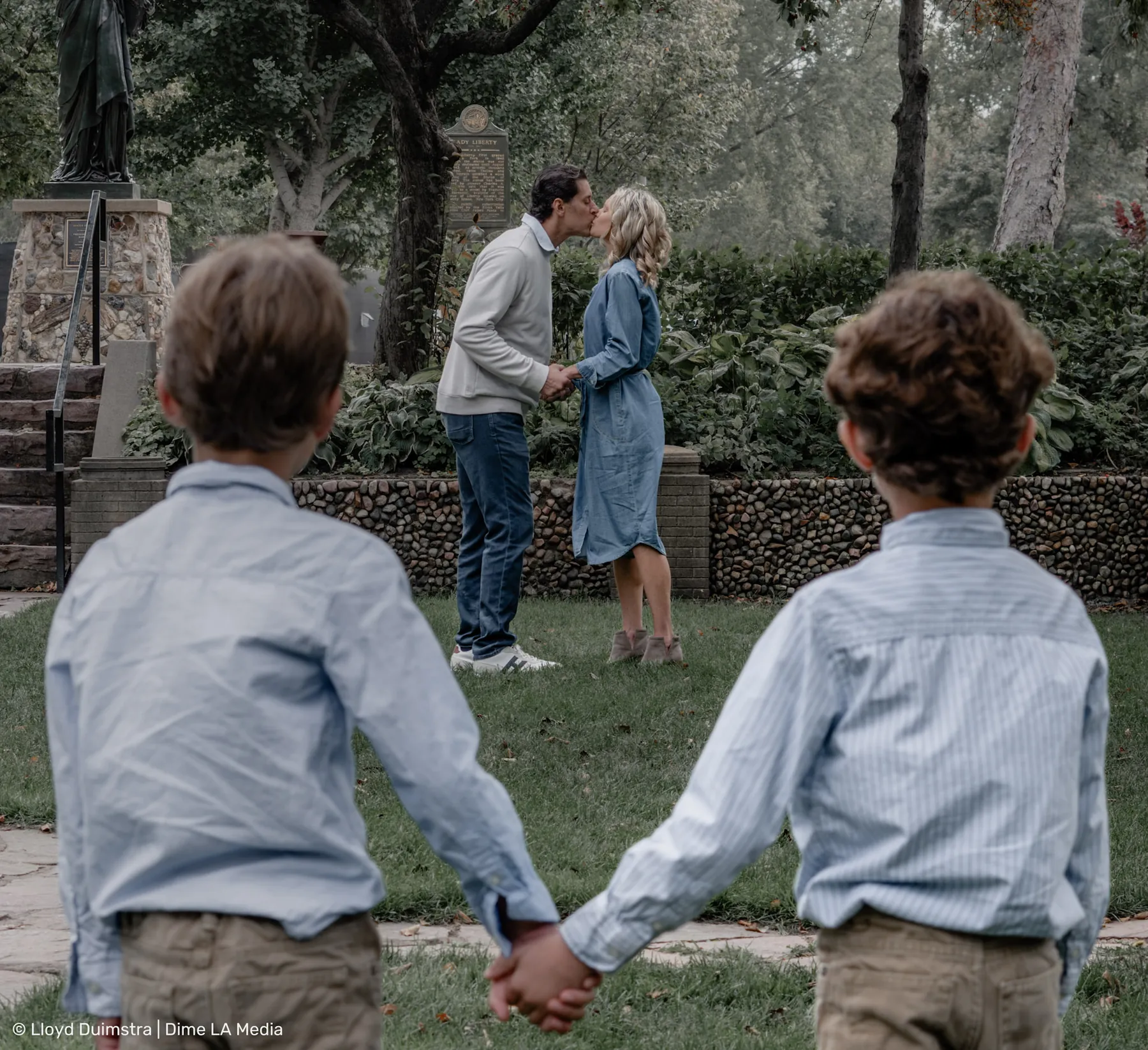 Brothers holding hands while mom and dad share a moment behind