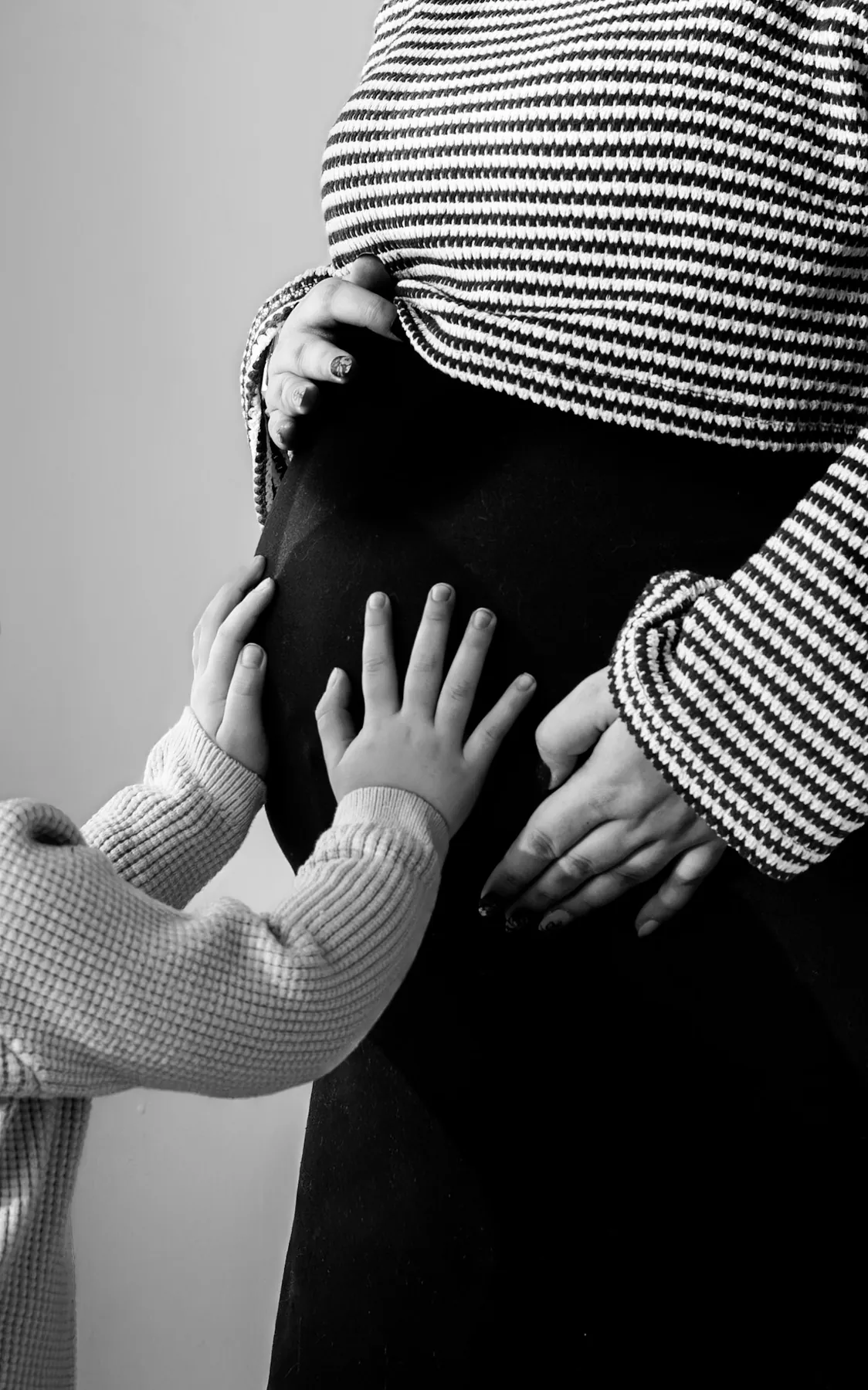 Little hands and parent hands resting on the baby bump