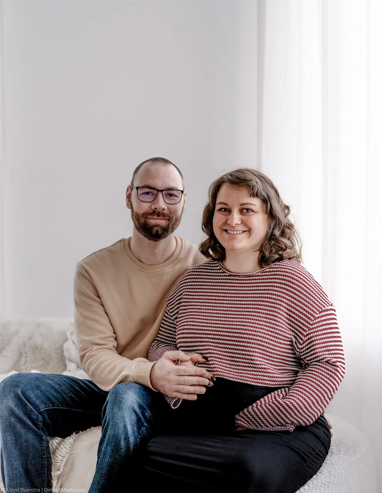 Expecting couple seated together in the studio