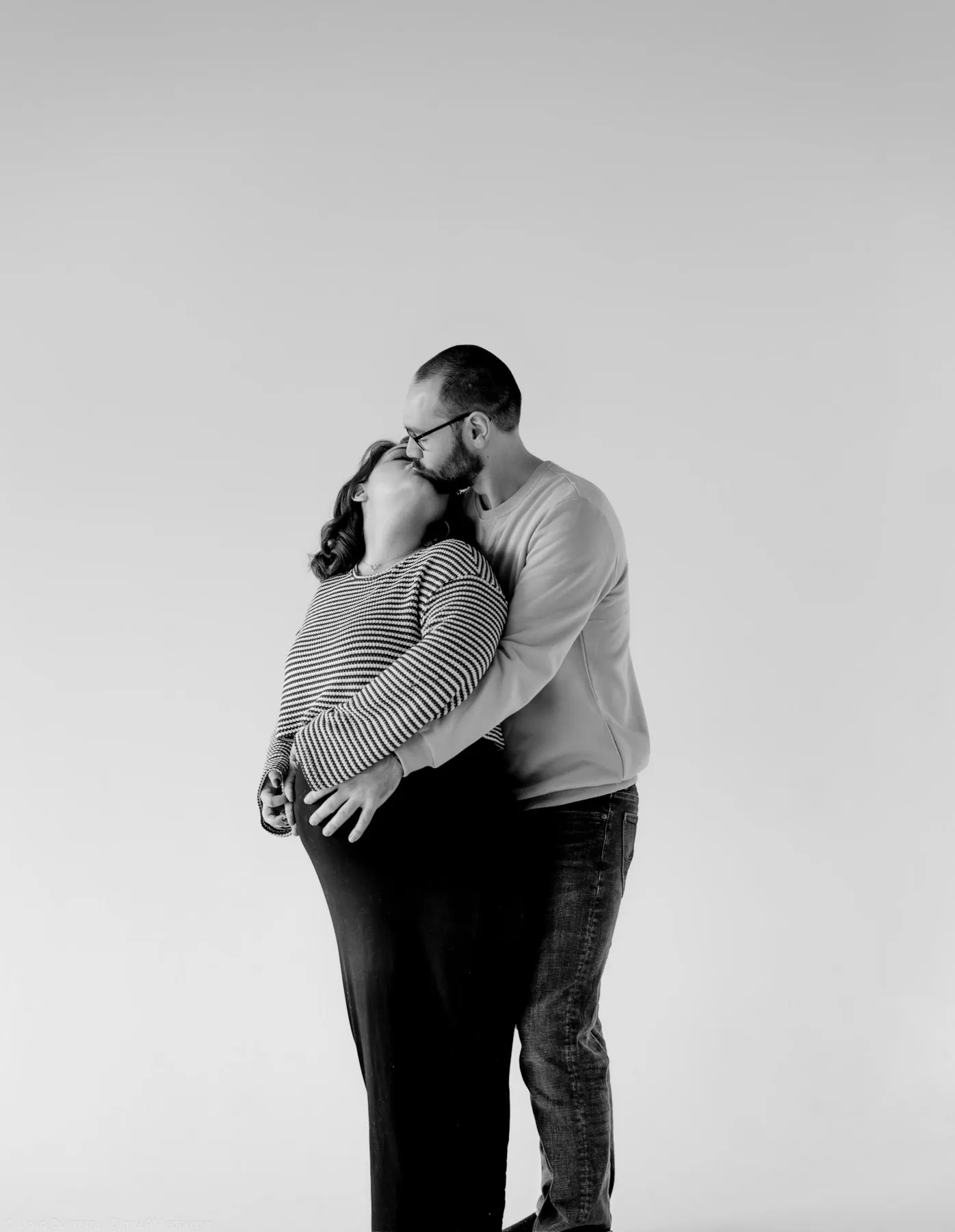Black and white maternity portrait of a kiss over the baby bump
