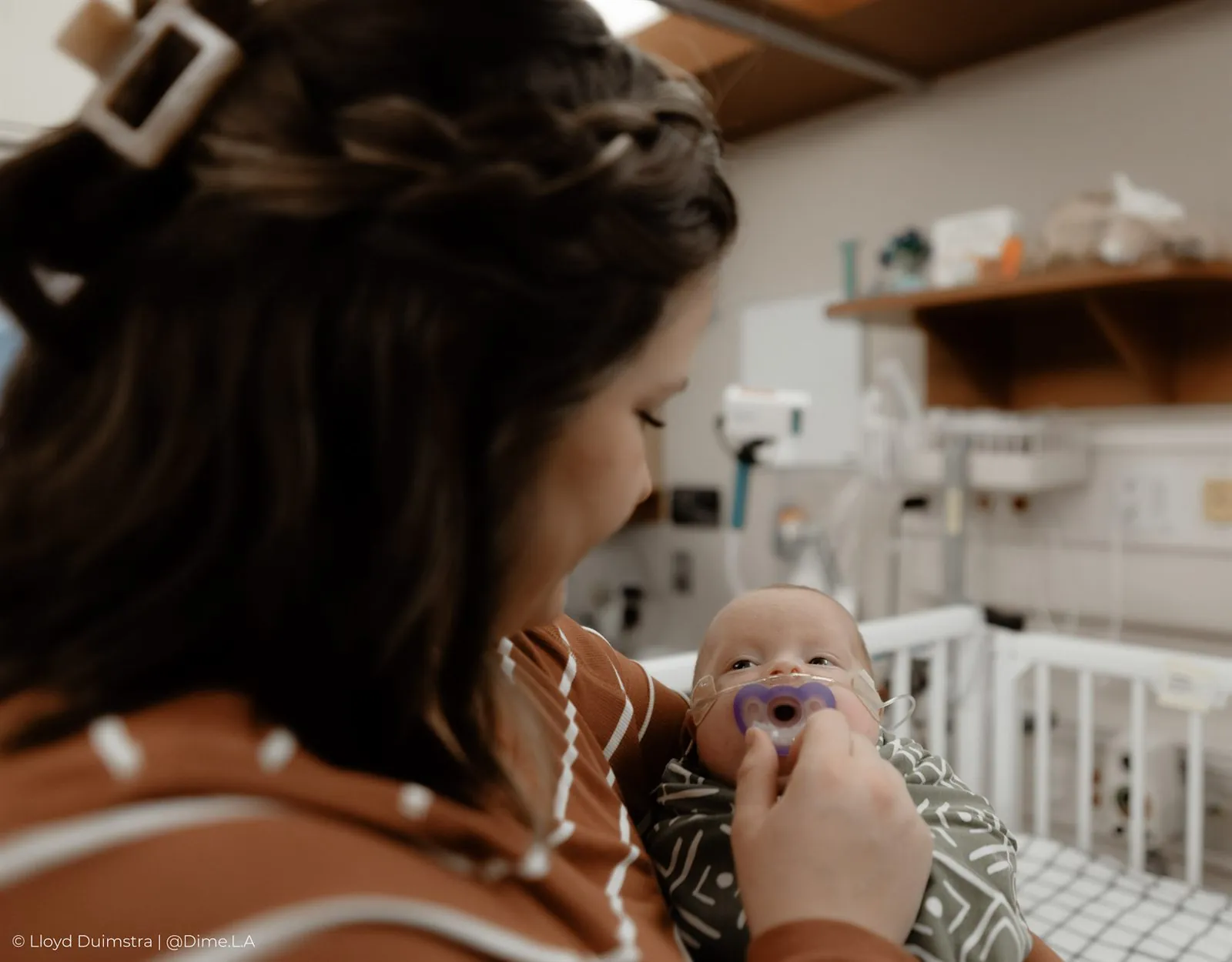 Mom giving her newborn his pacifier in the NICU