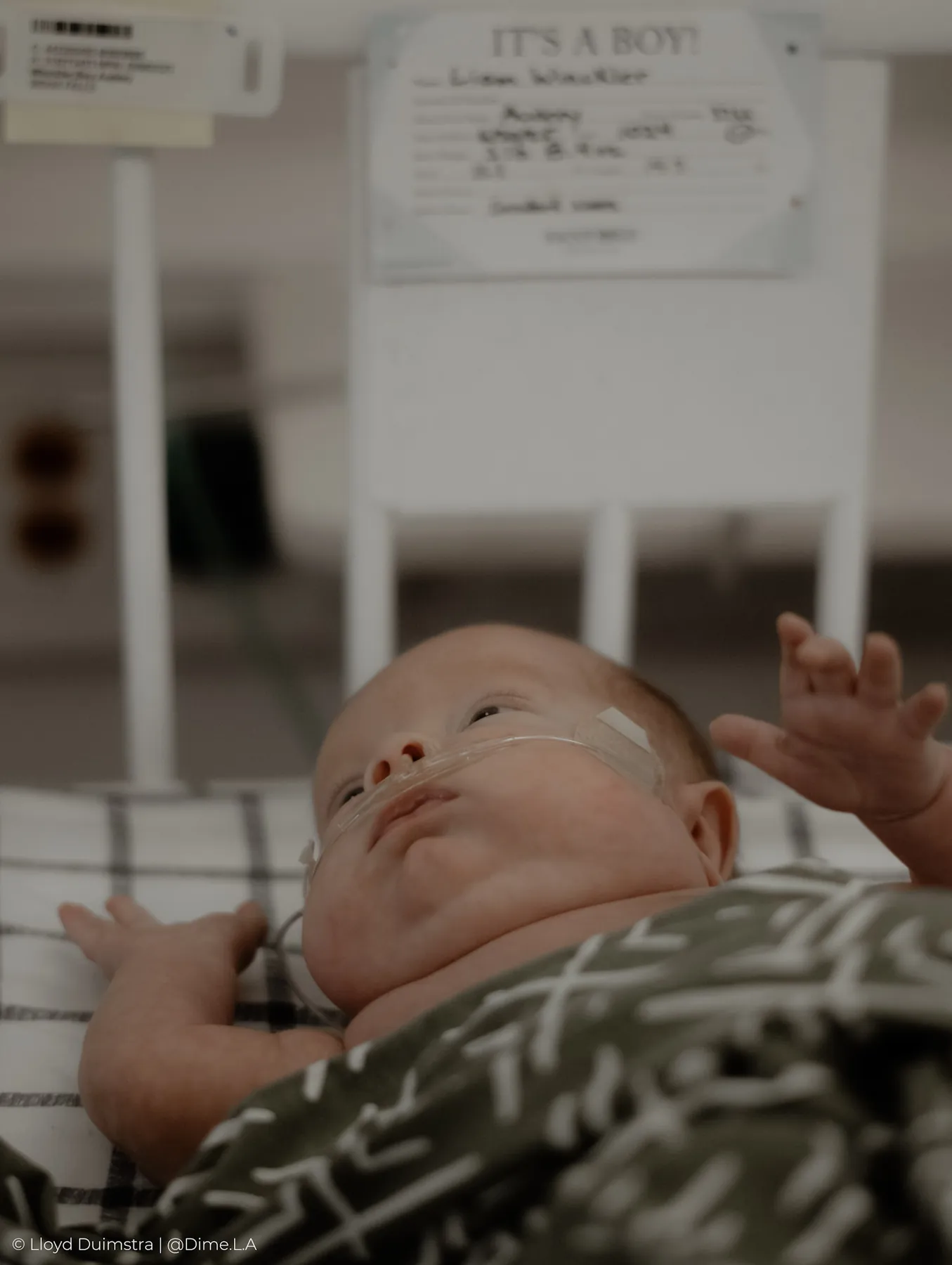 Newborn stretching on a checked blanket in the NICU