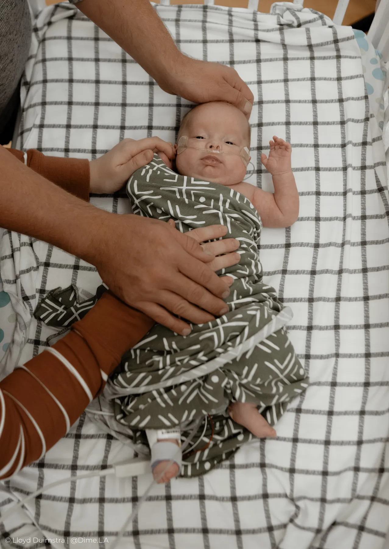 Parents soothing their swaddled newborn in the NICU