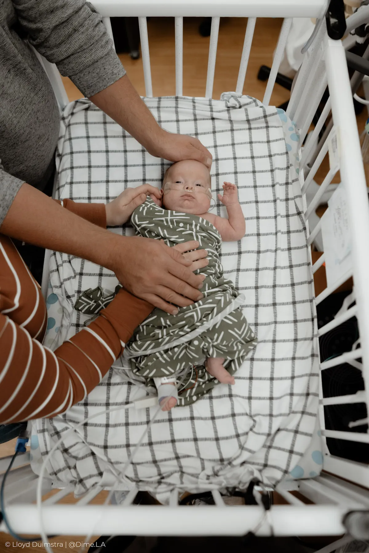 Mom tucking her newborn into the hospital crib