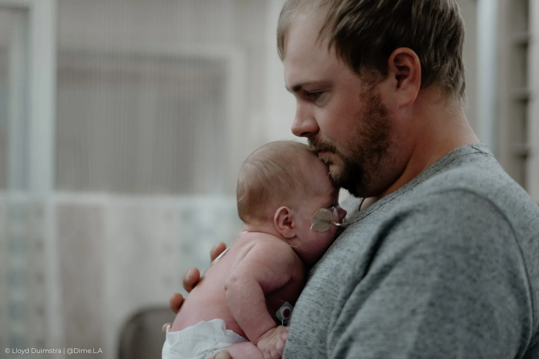 Dad resting his cheek against his newborn in the NICU