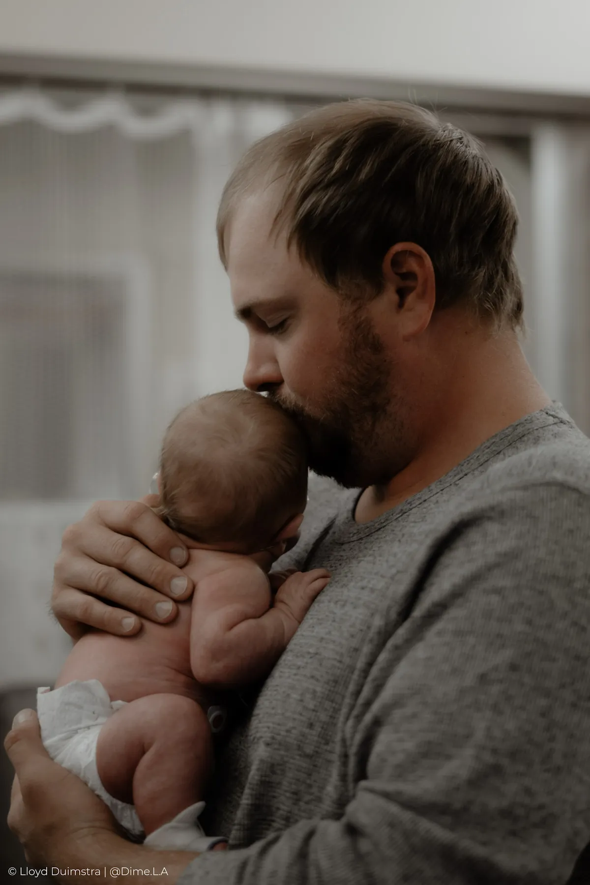 Dad kissing his newborn son’s head in the NICU