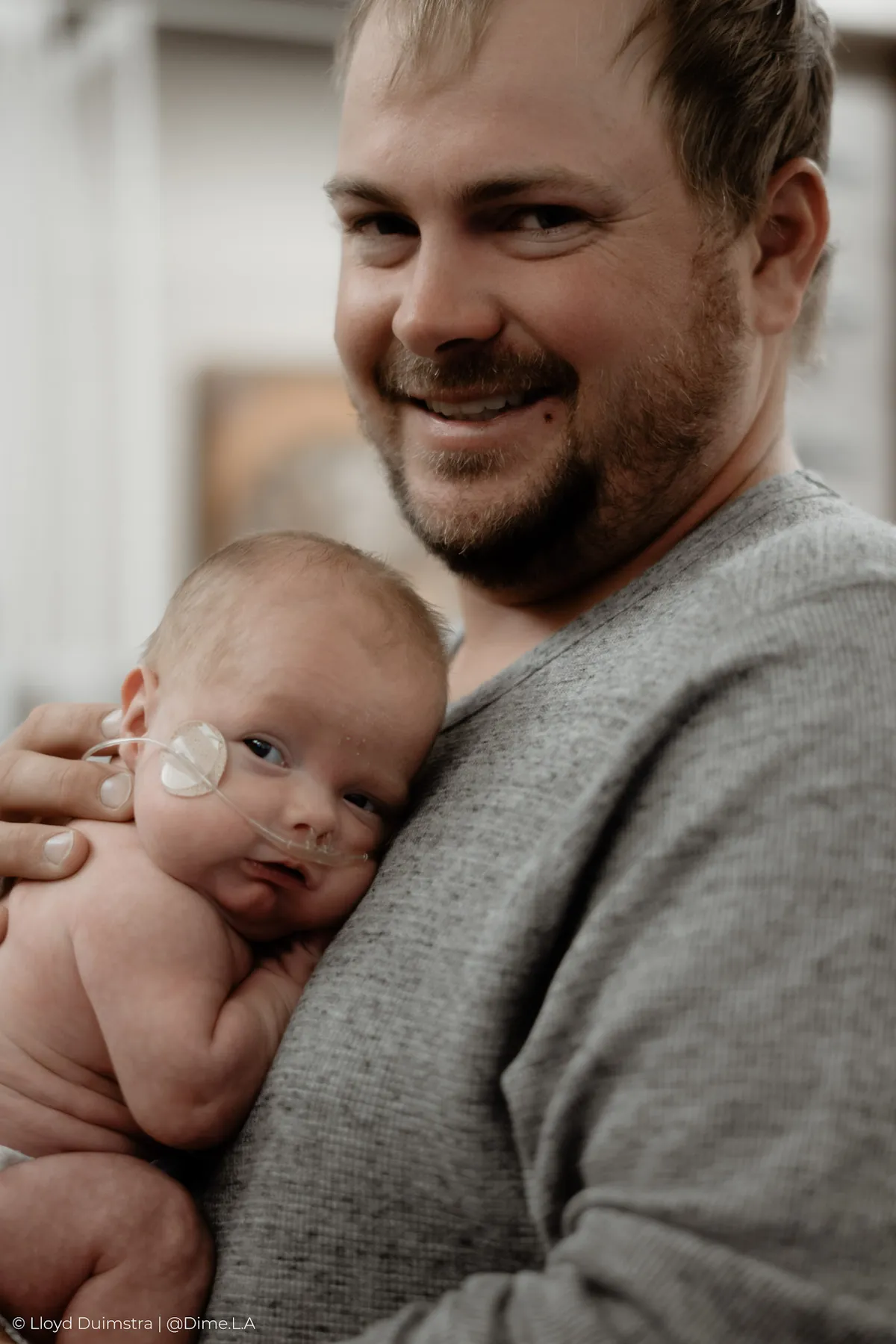 Dad smiling down at his newborn son, NICU documentary session