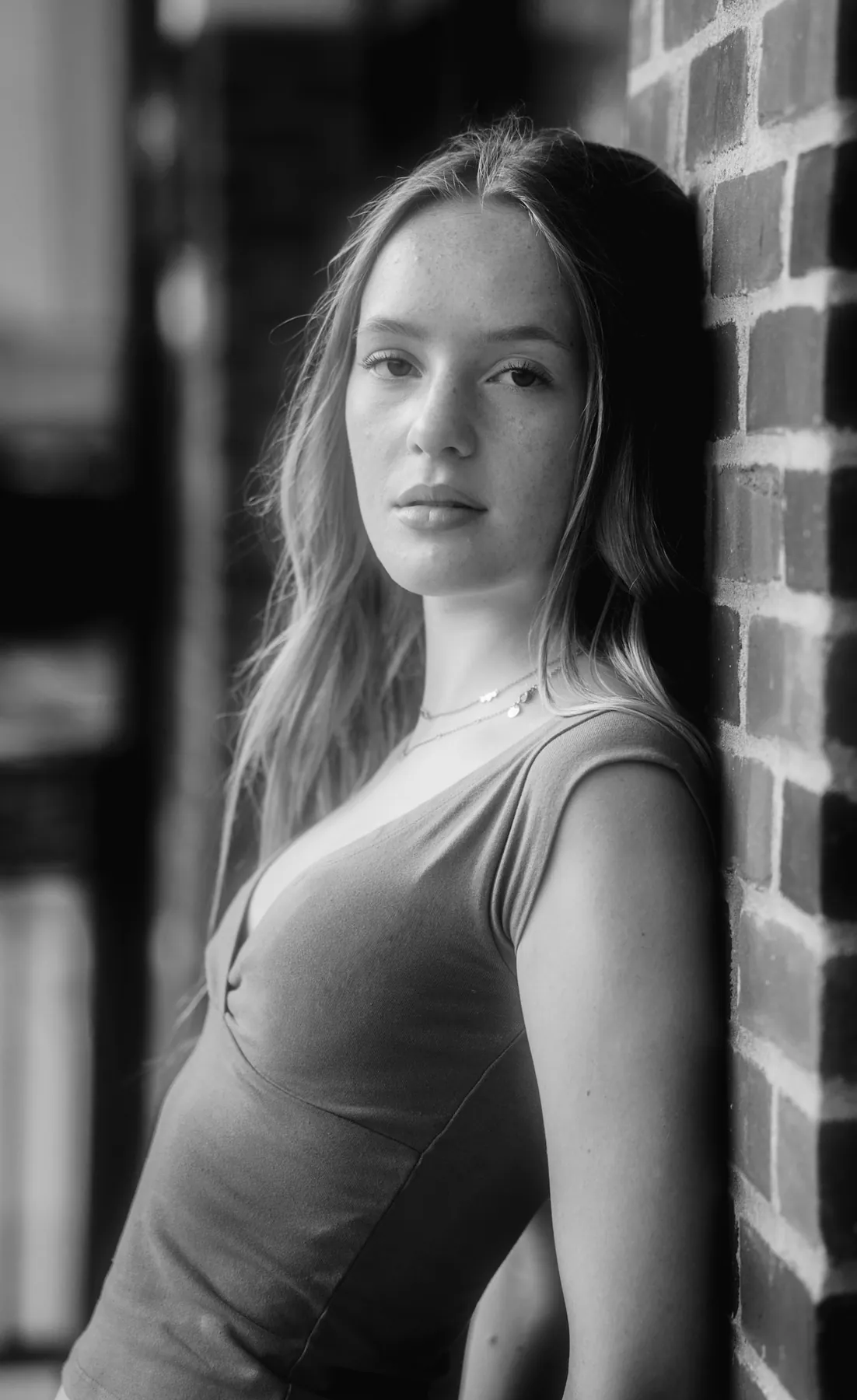Black and white editorial senior portrait of Scout against a brick wall in downtown Sioux Falls