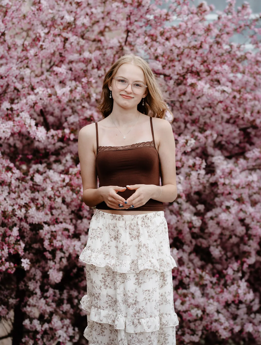 Syd Patzwald senior portrait against a wall of pink crabapple blossoms