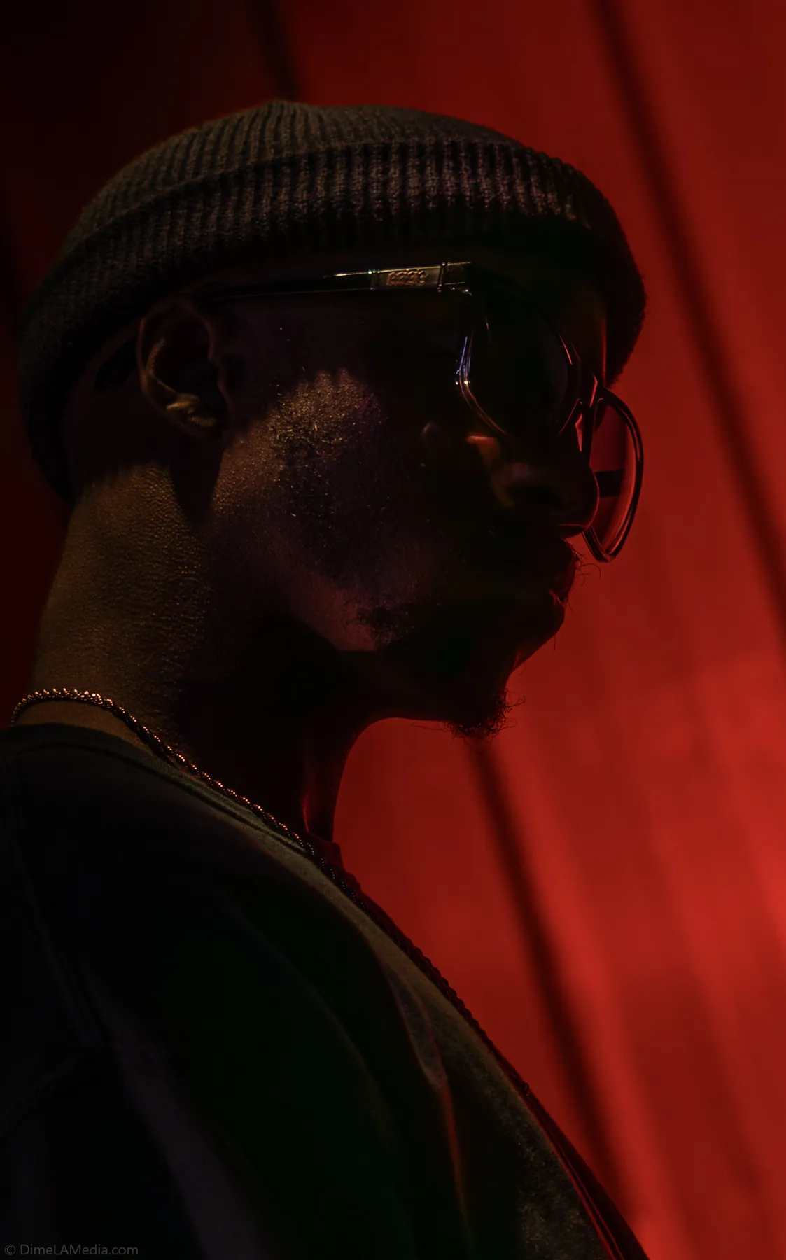 Dramatic red-lit studio portrait of a man in a beanie
