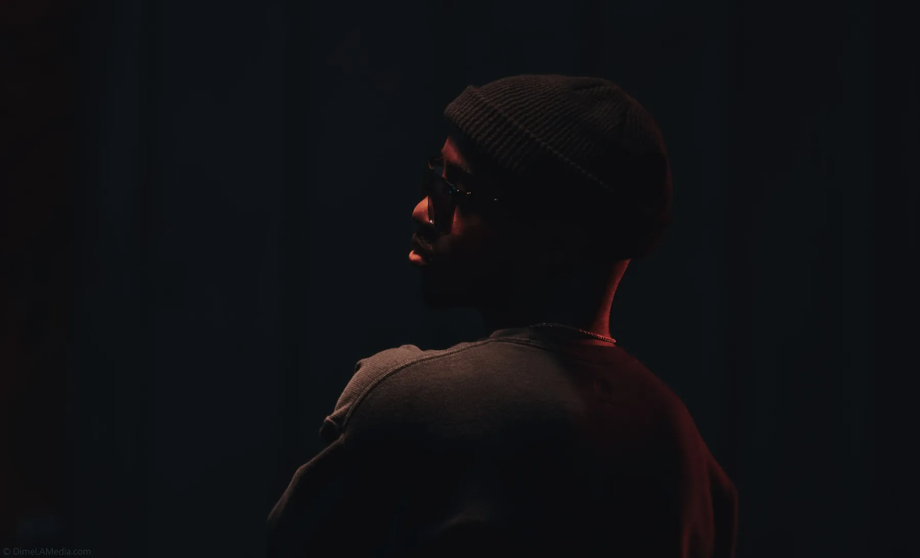 Shadowed studio profile with a whisper of red light
