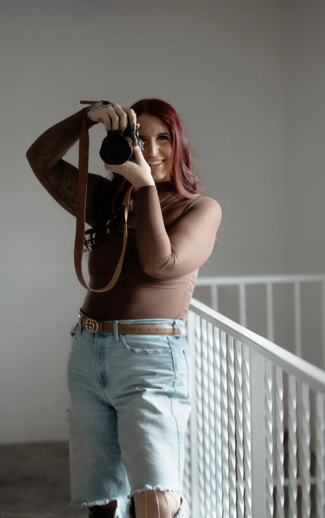 Photographer with camera in hand by a white railing