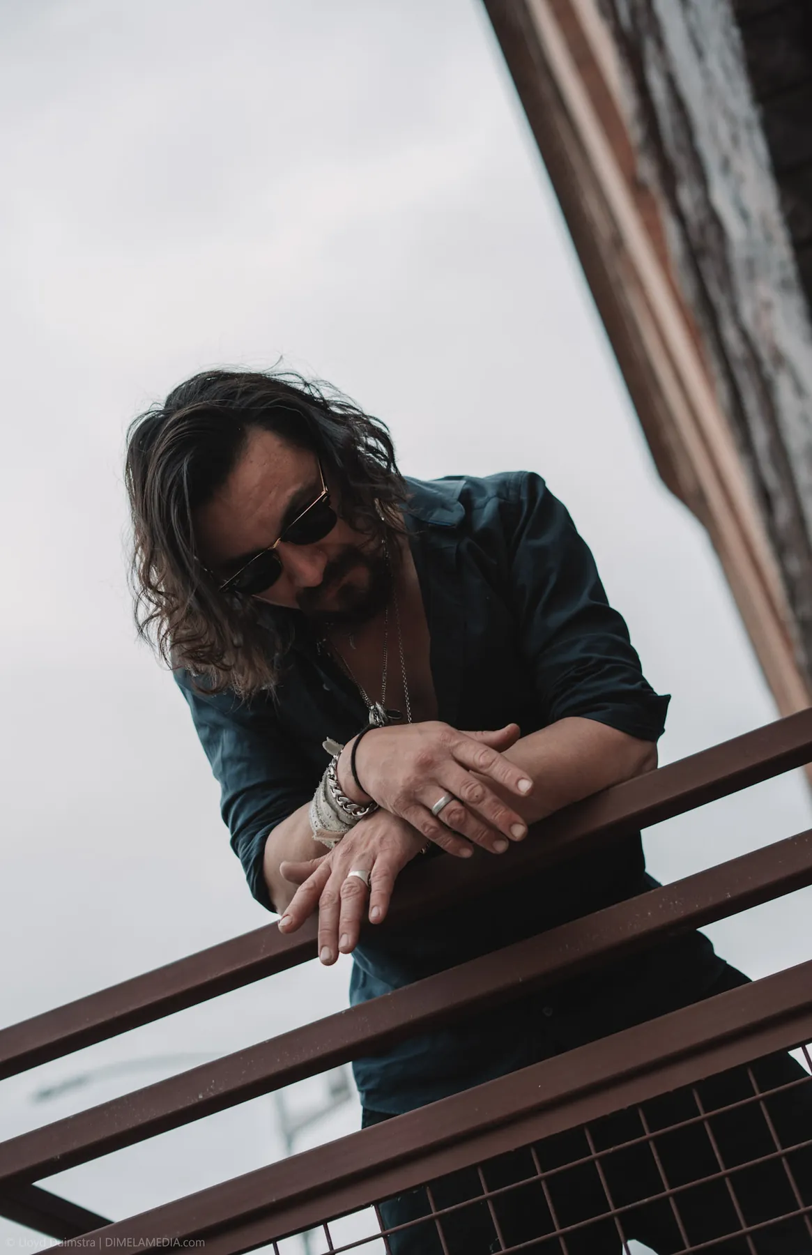 Editorial portrait of a musician leaning on a balcony rail