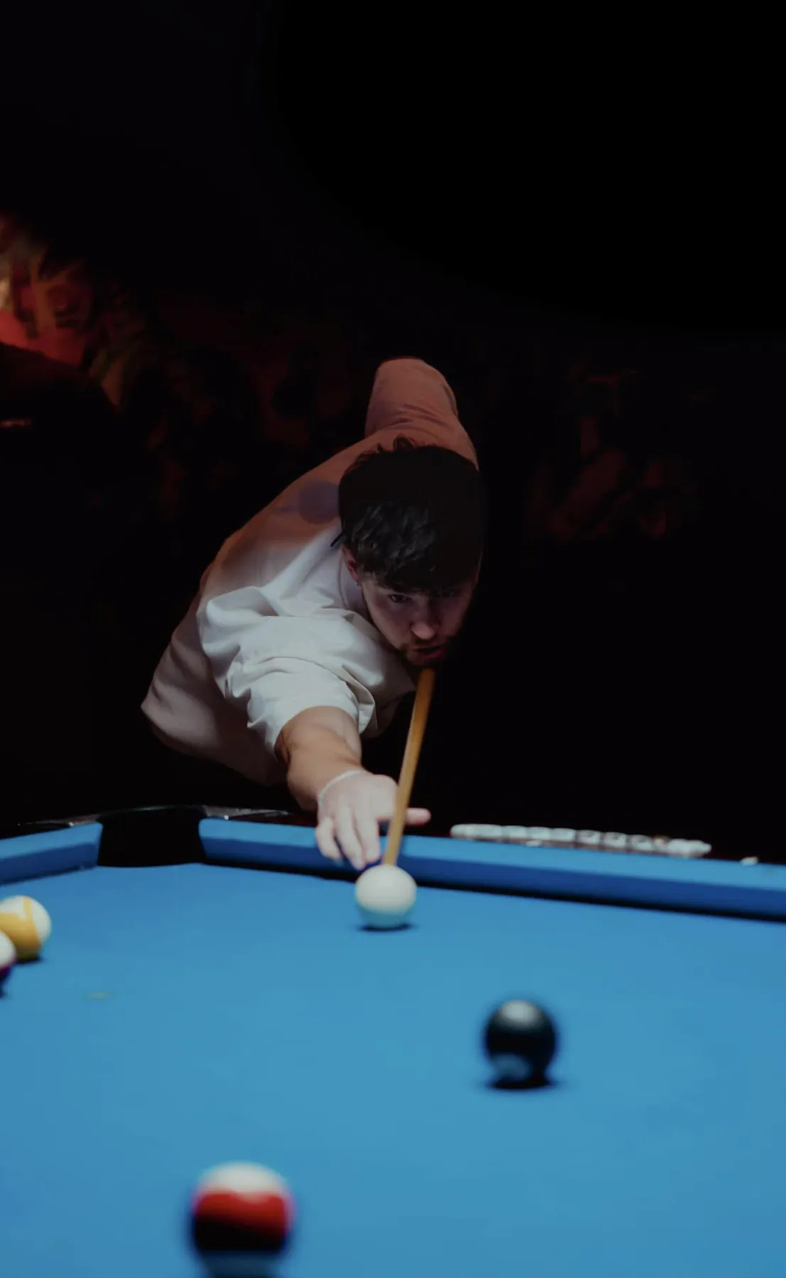 Low-light portrait lining up a shot at the pool table