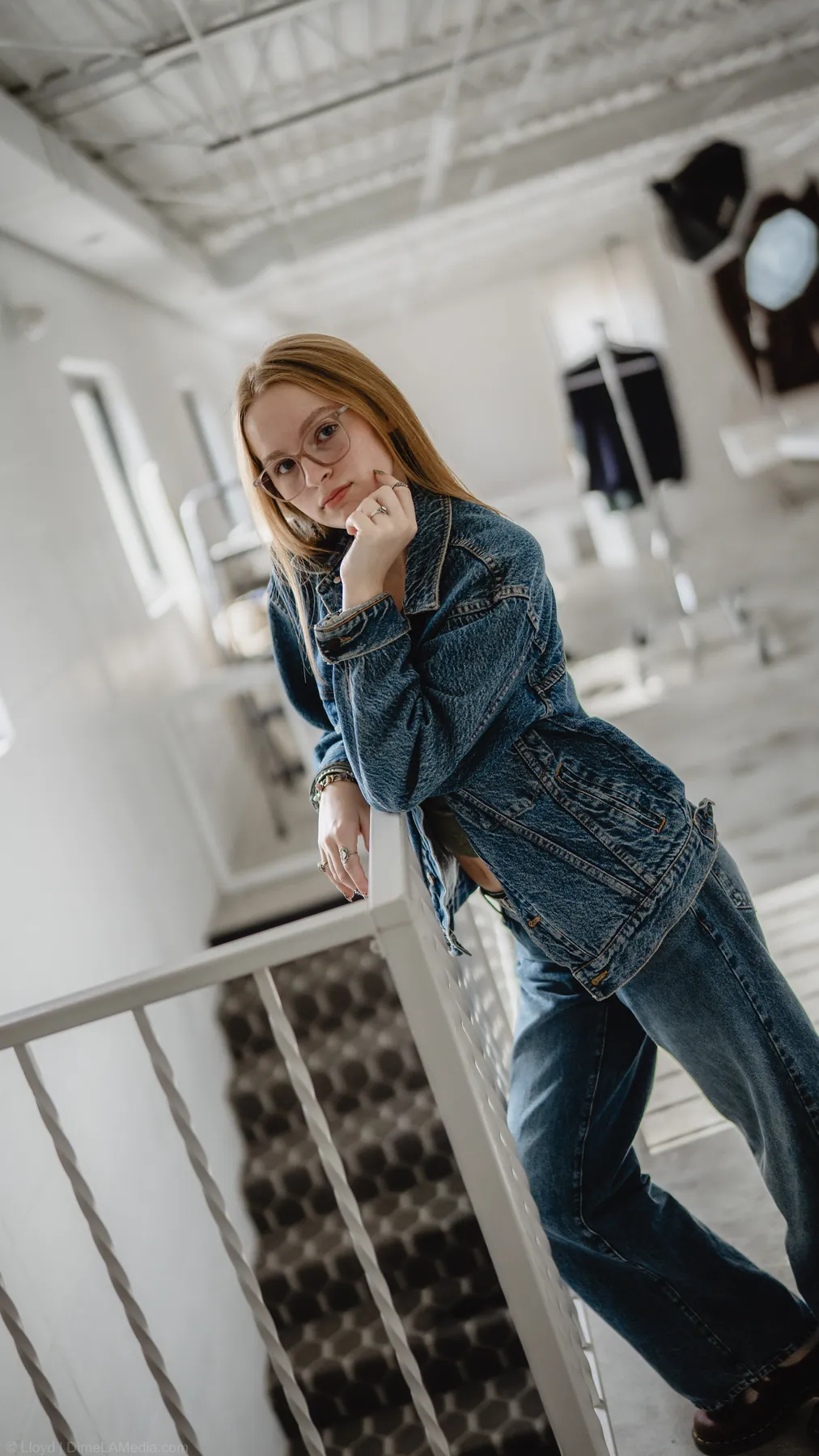 Wide environmental shot of Syd Patzwald leaning on a staircase railing in the studio