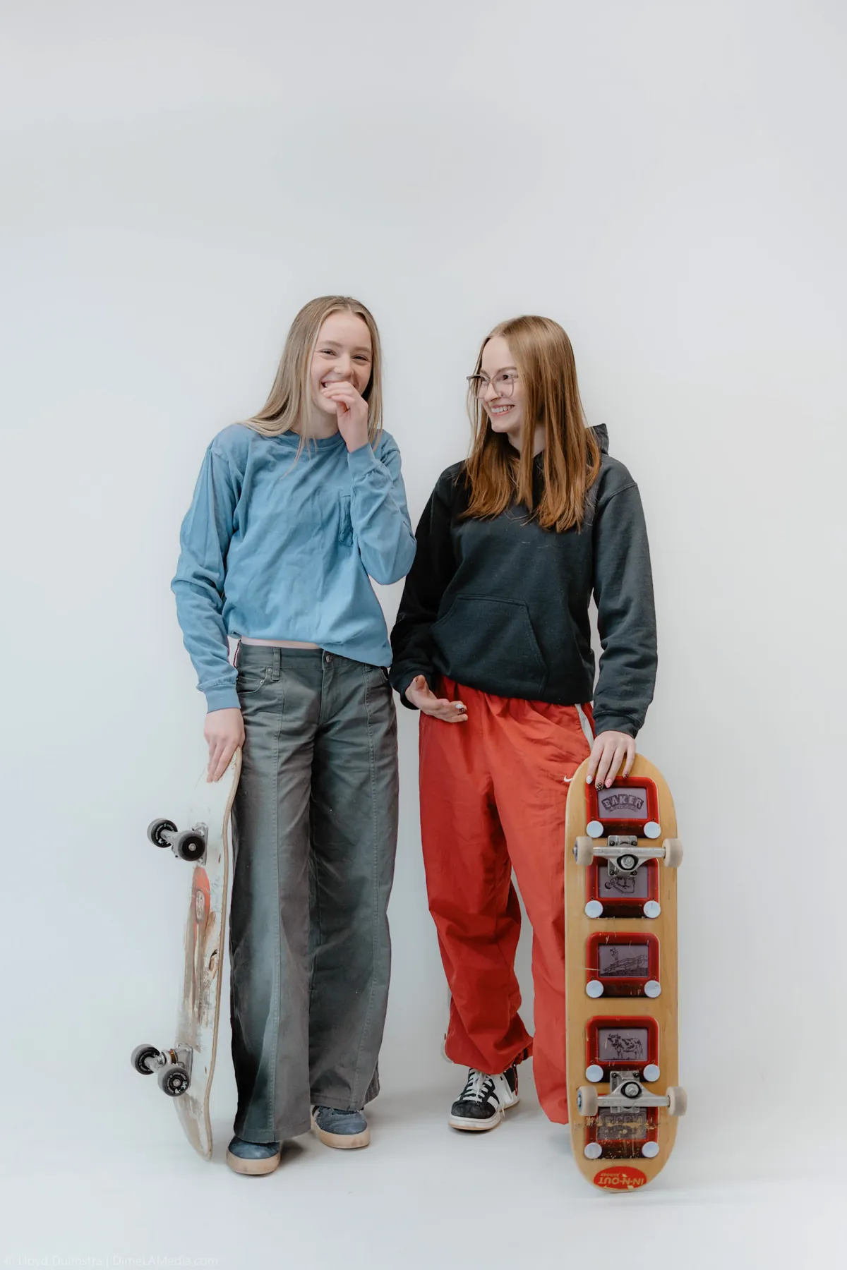 Syd Patzwald and a friend with skateboards on a white studio backdrop