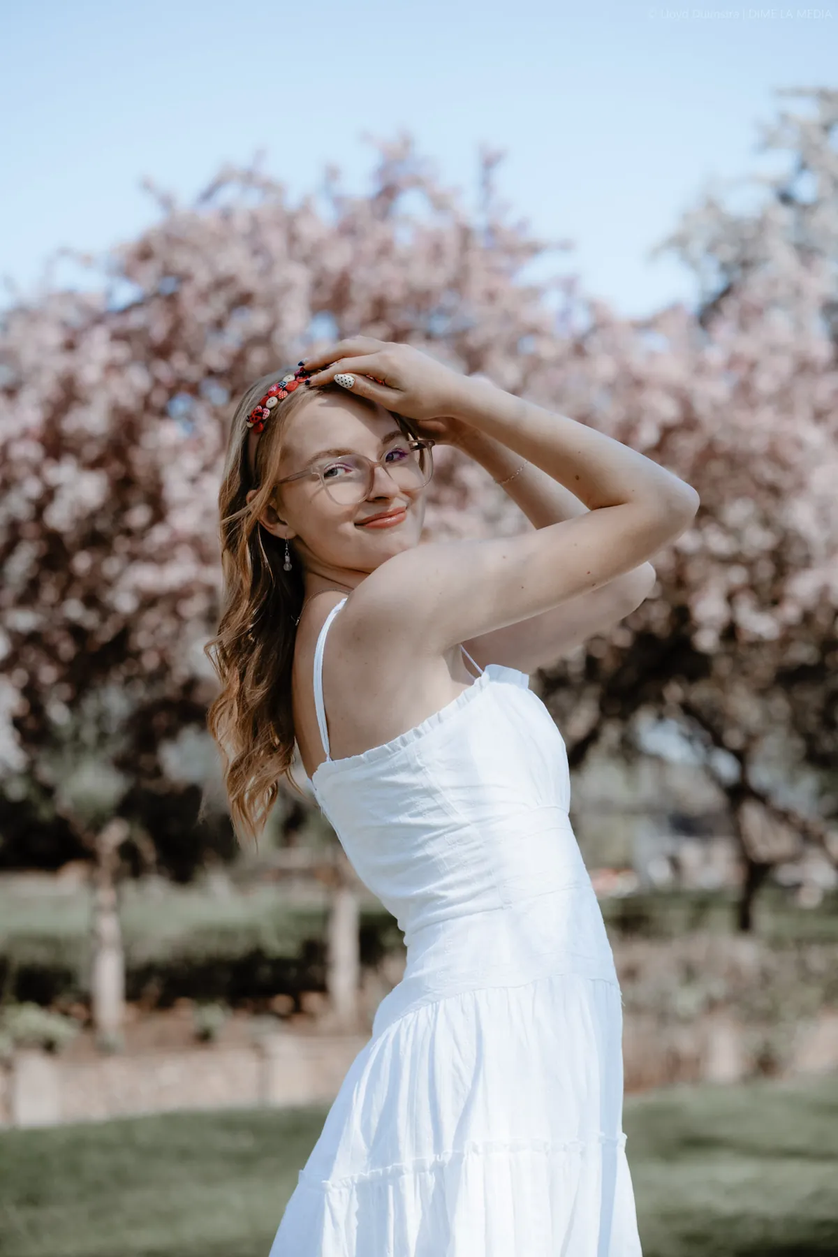 Syd Patzwald in a white dress beside a blossoming crabapple tree