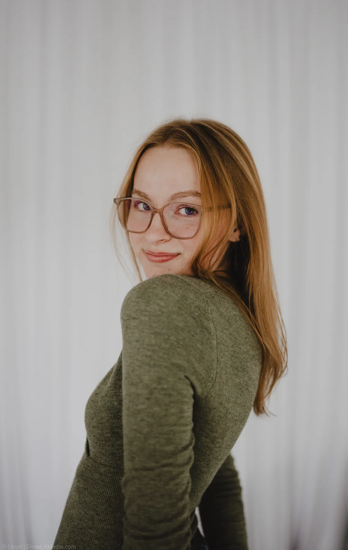 Syd Patzwald glancing over her shoulder in a sweater, studio portrait variation