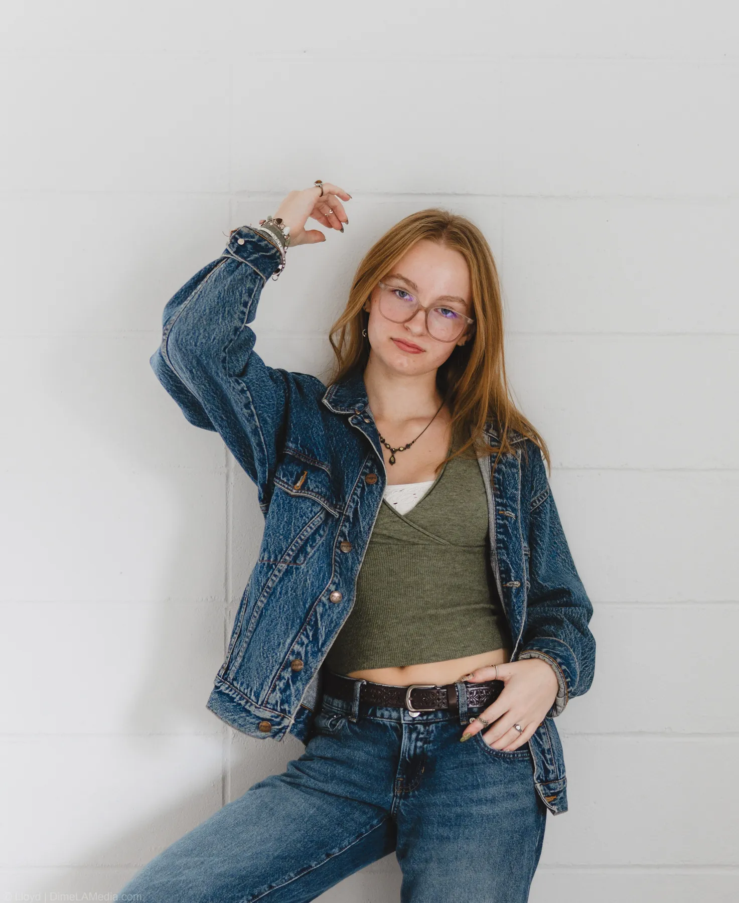 Syd Patzwald in a denim jacket leaning against a cinderblock wall, studio portrait