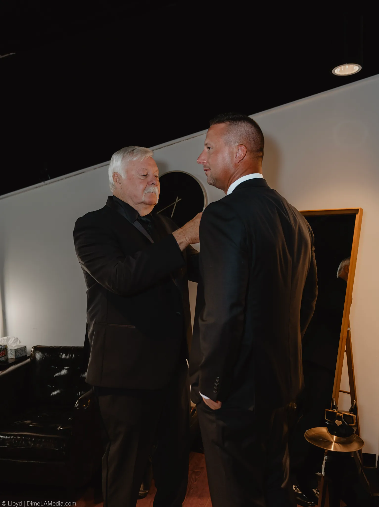 Groom and an older man talking face to face in a dressing room