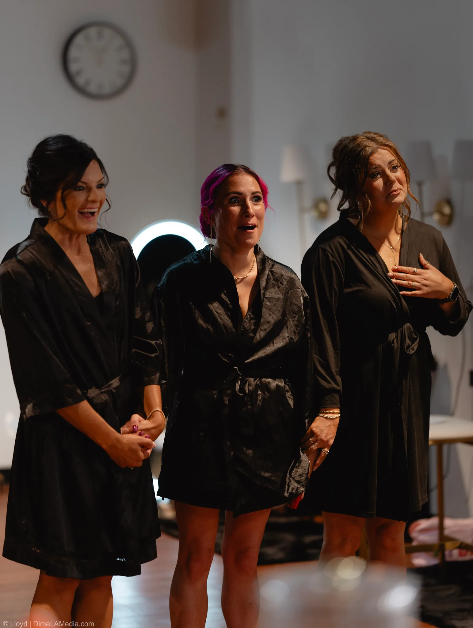 Three bridesmaids in black robes, one with a hand over her heart