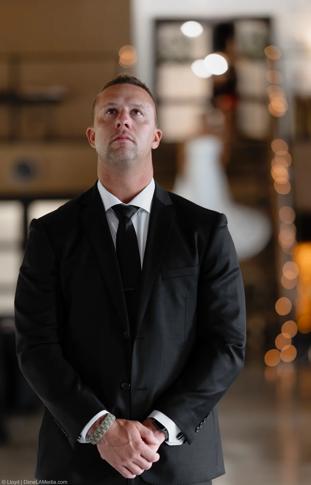 Groom in a dark suit waiting alone and looking up