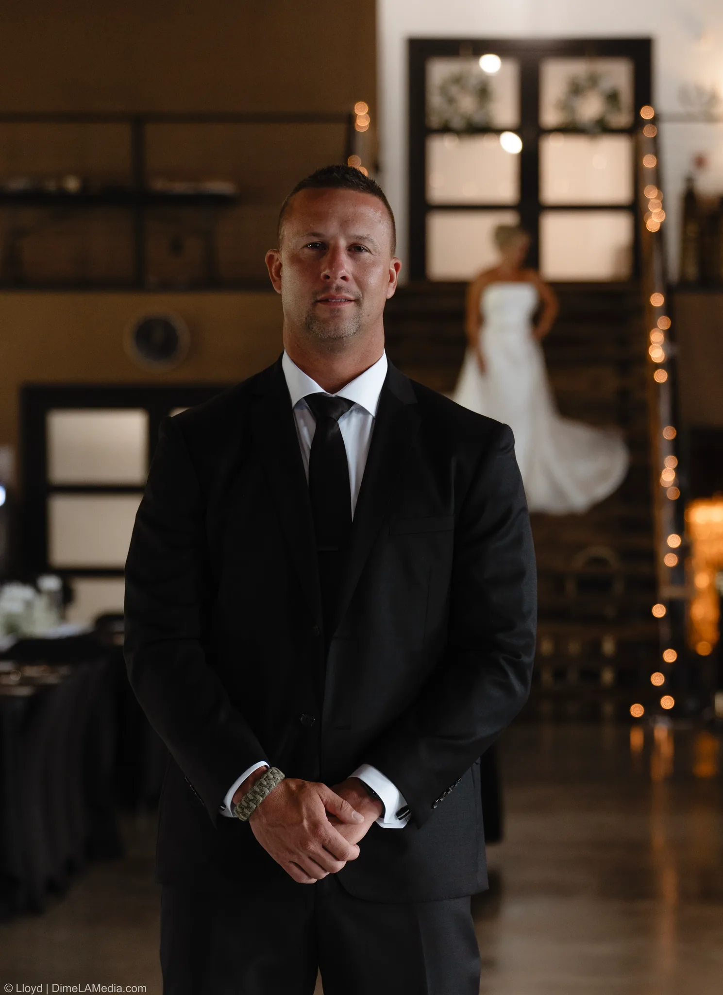 Groom standing with his hands clasped, the bride visible in the background at the first look, Sioux Falls SD
