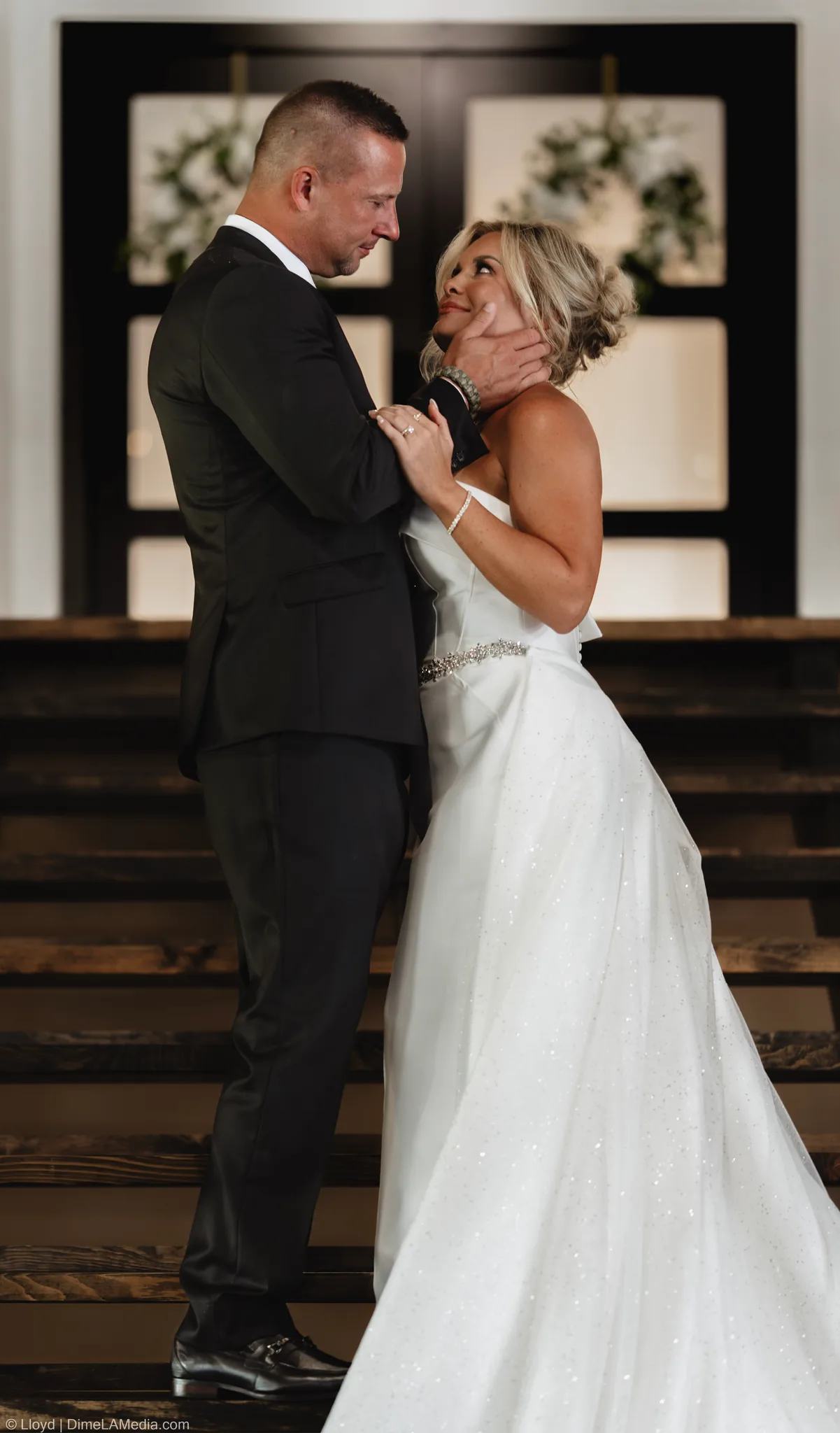 Bride and groom in a close embrace in front of tall wooden doors