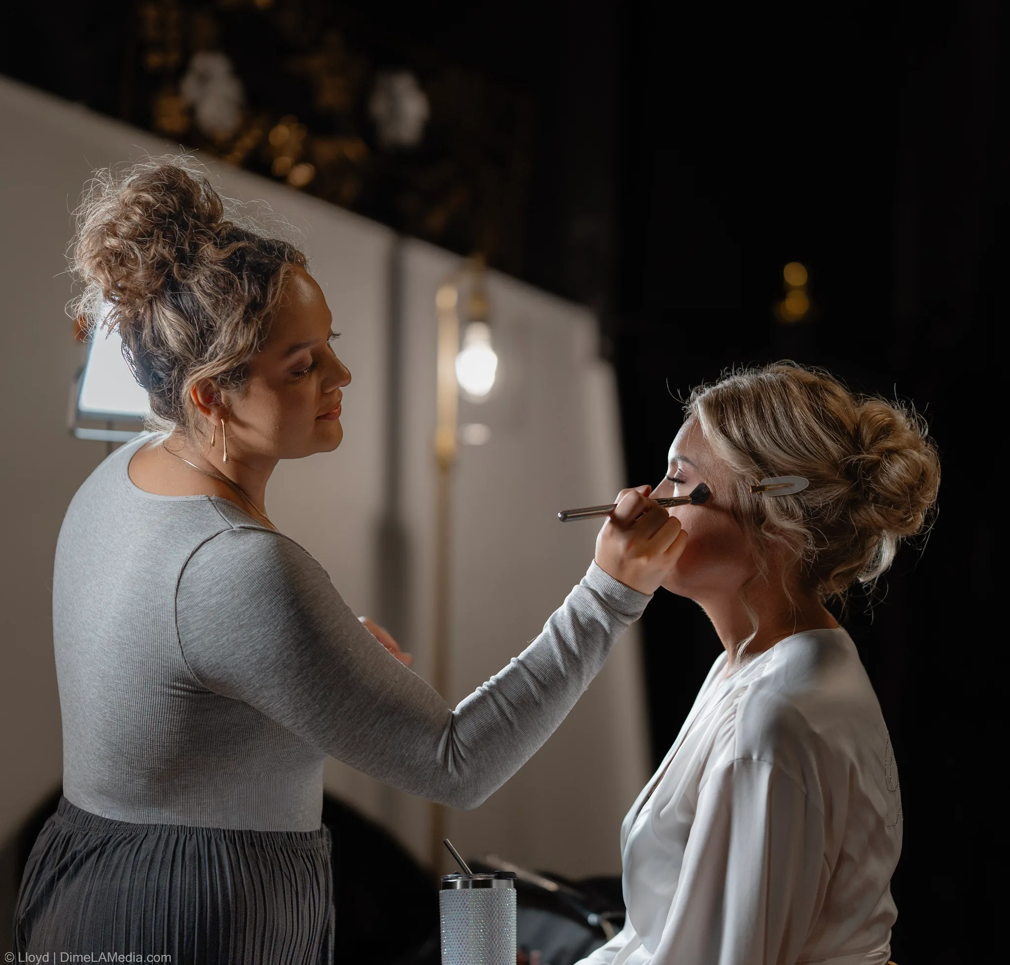 Makeup artist applying a bride's makeup in soft warm light