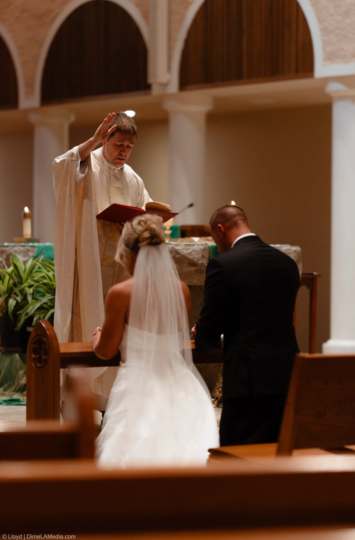 Priest raising his hand in blessing over the couple at the altar