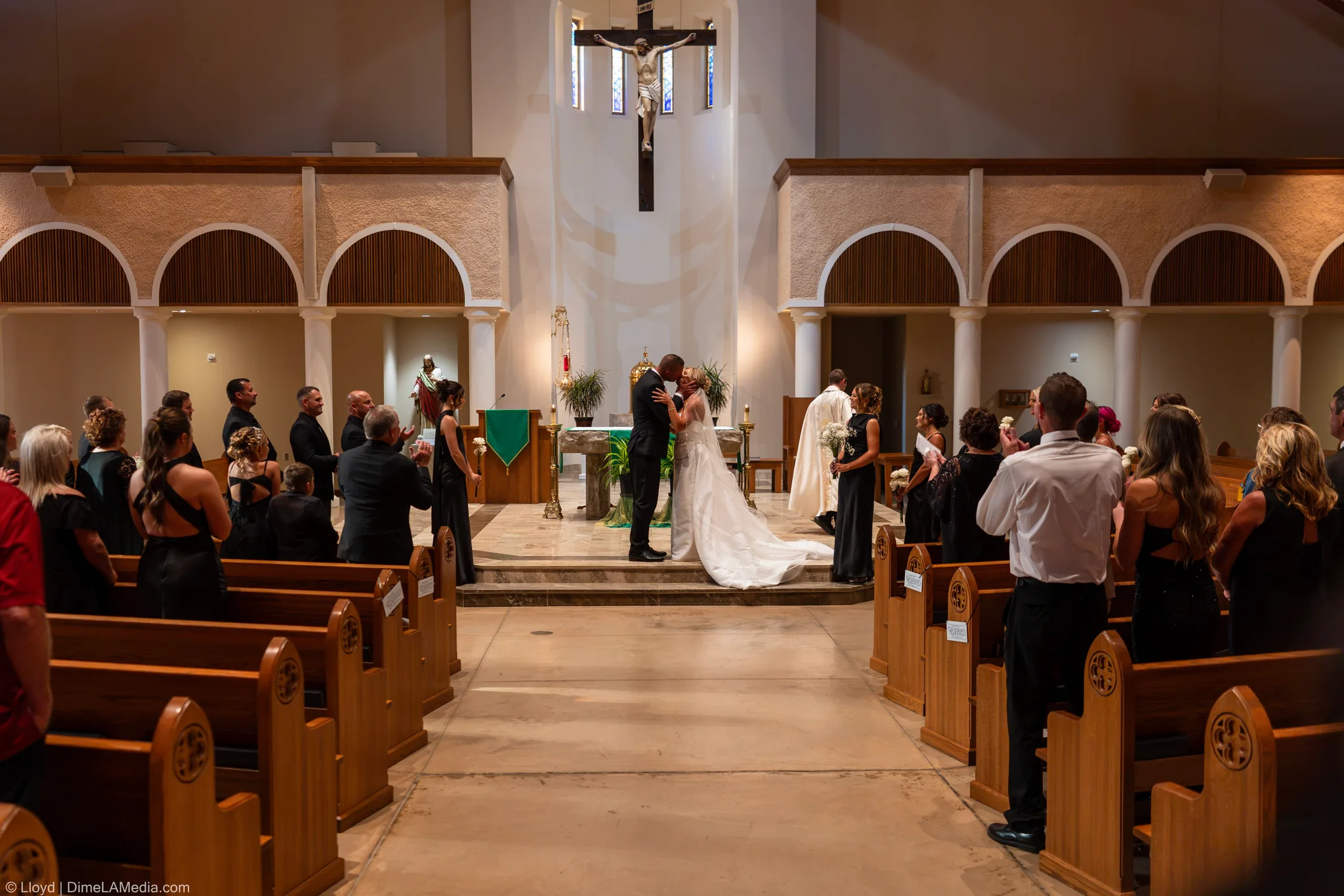 Wide view of the couple kissing at the altar, guests watching from the pews, Sioux Falls SD