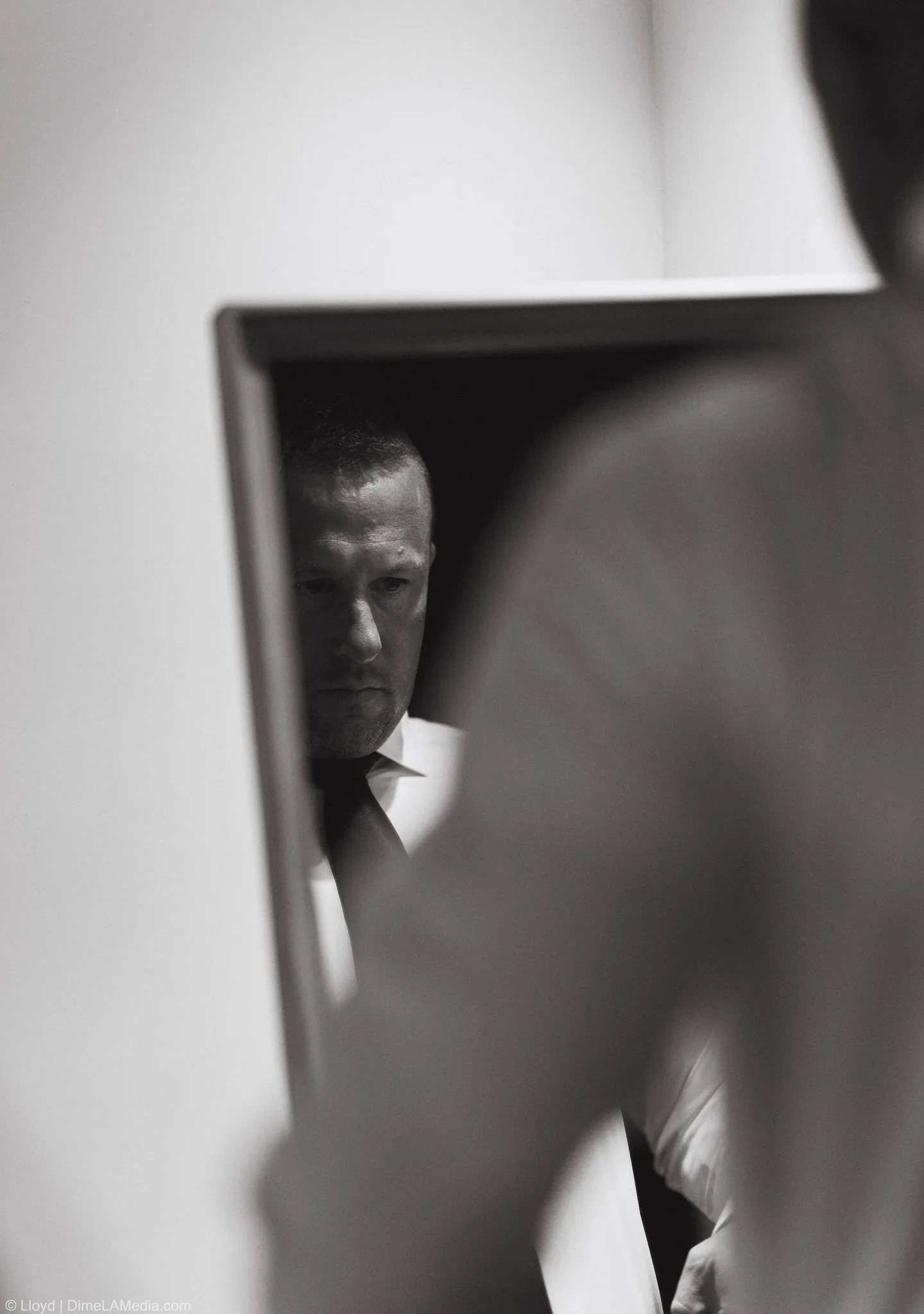 Groom reflected in a mirror in a dim room, black and white