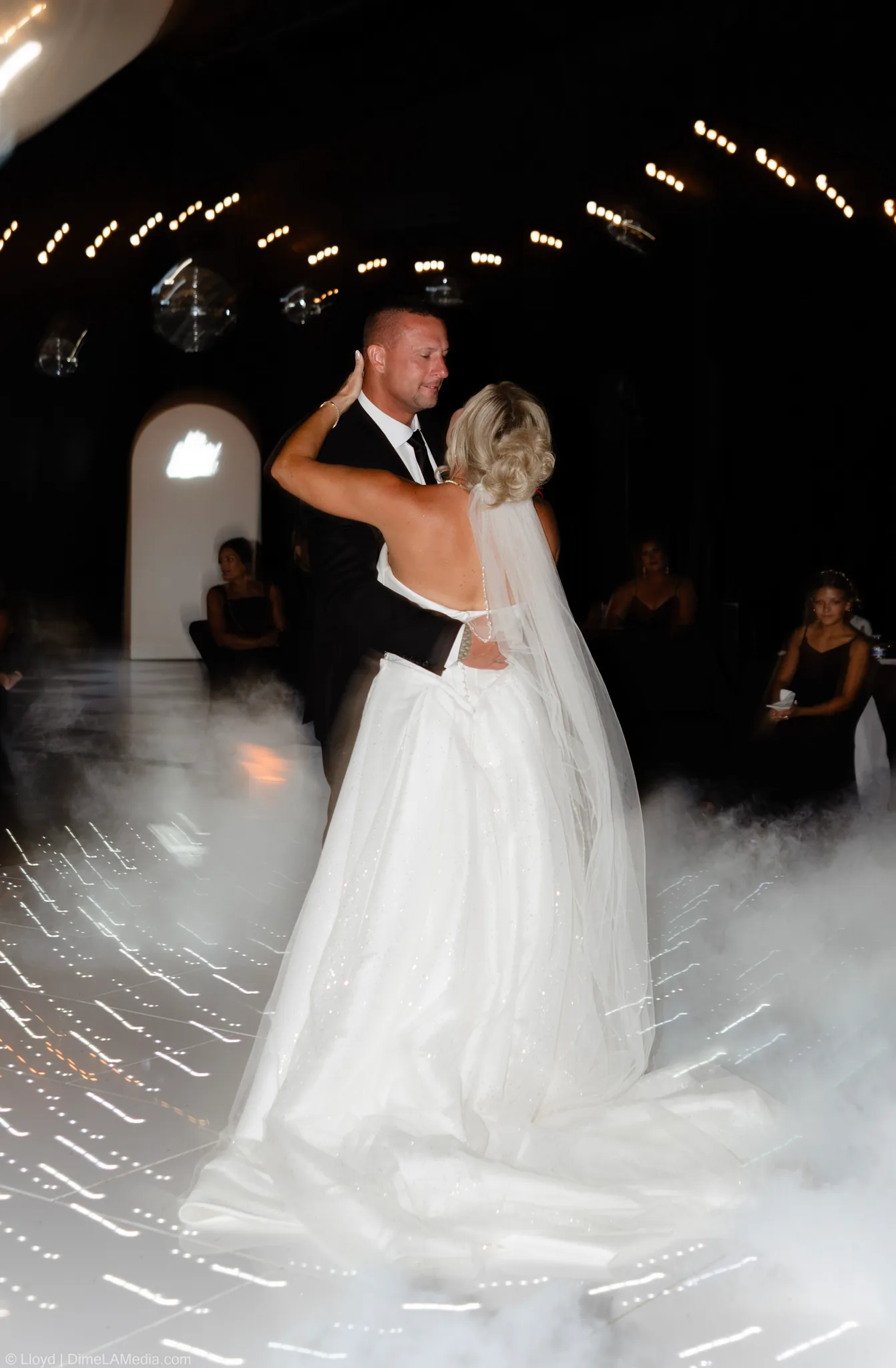 First dance through drifting fog under string lights