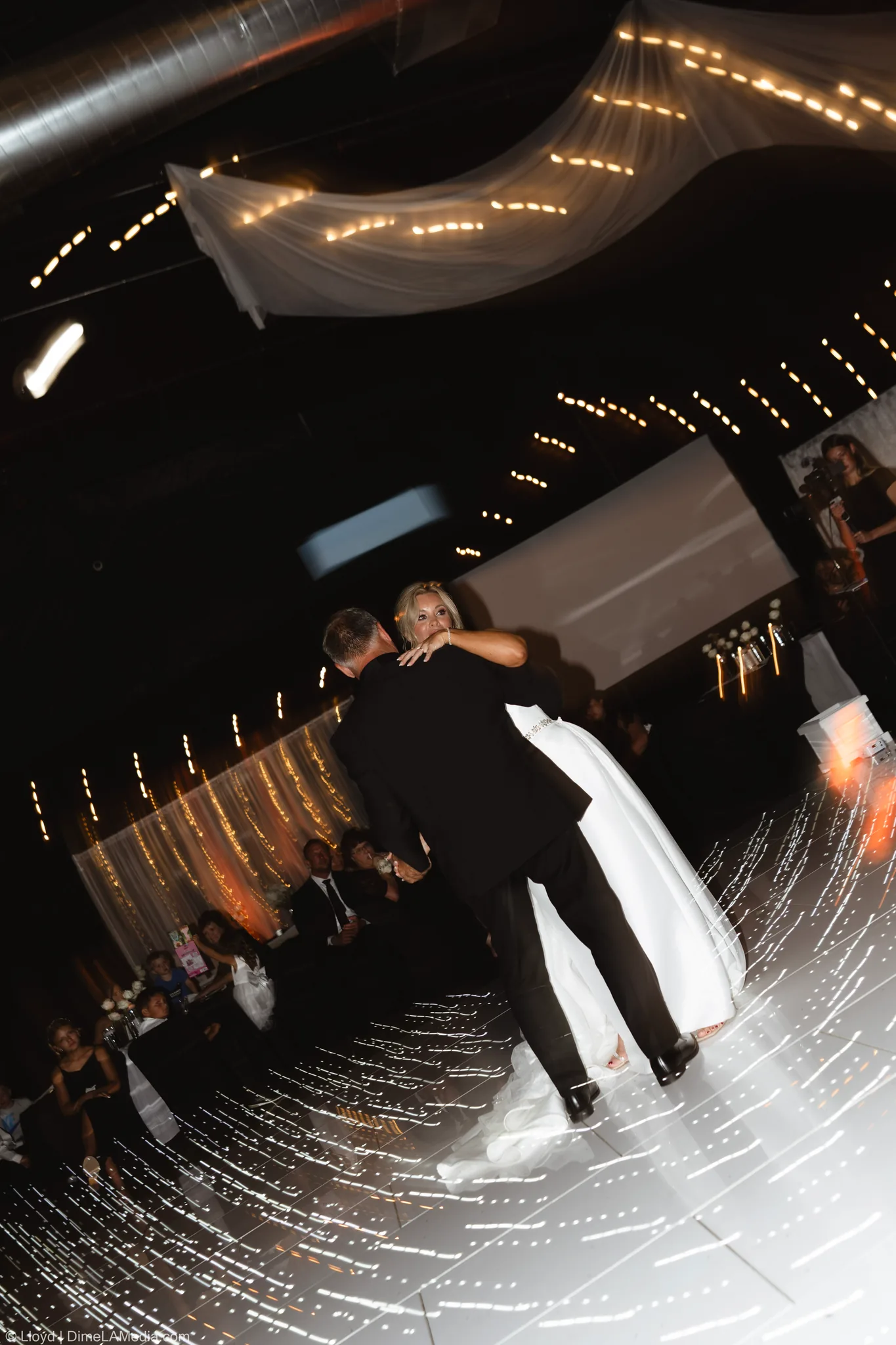 Groom spinning his bride across a lit dance floor