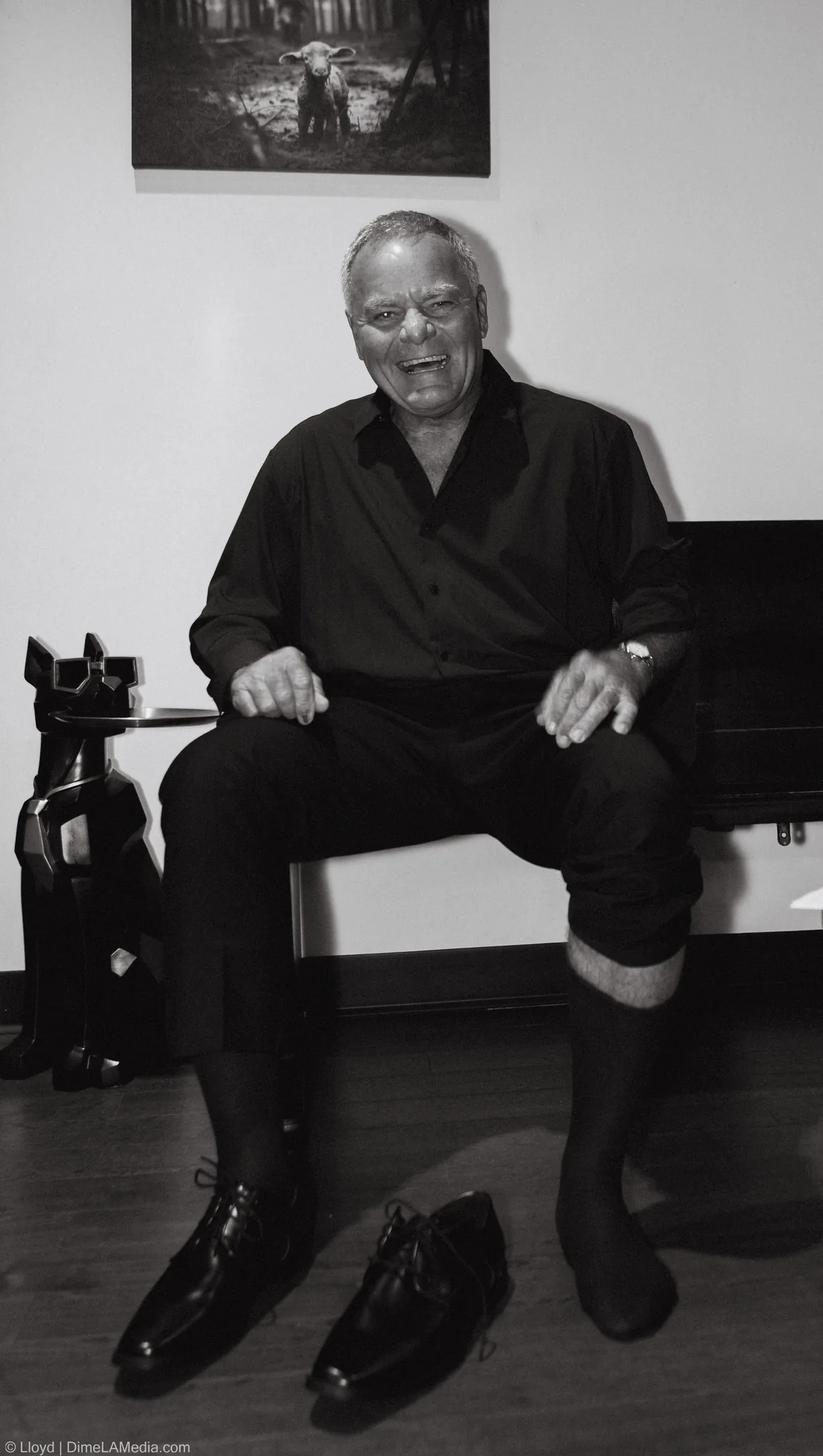 Older man in a black shirt sitting on a bench and laughing, black and white