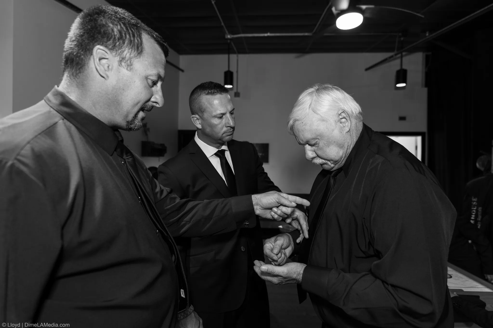 Men helping each other get dressed in a dressing room, black and white