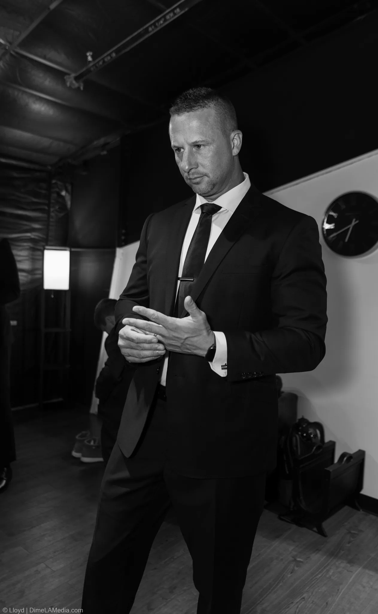 Groom in a dark suit and tie getting ready, black and white