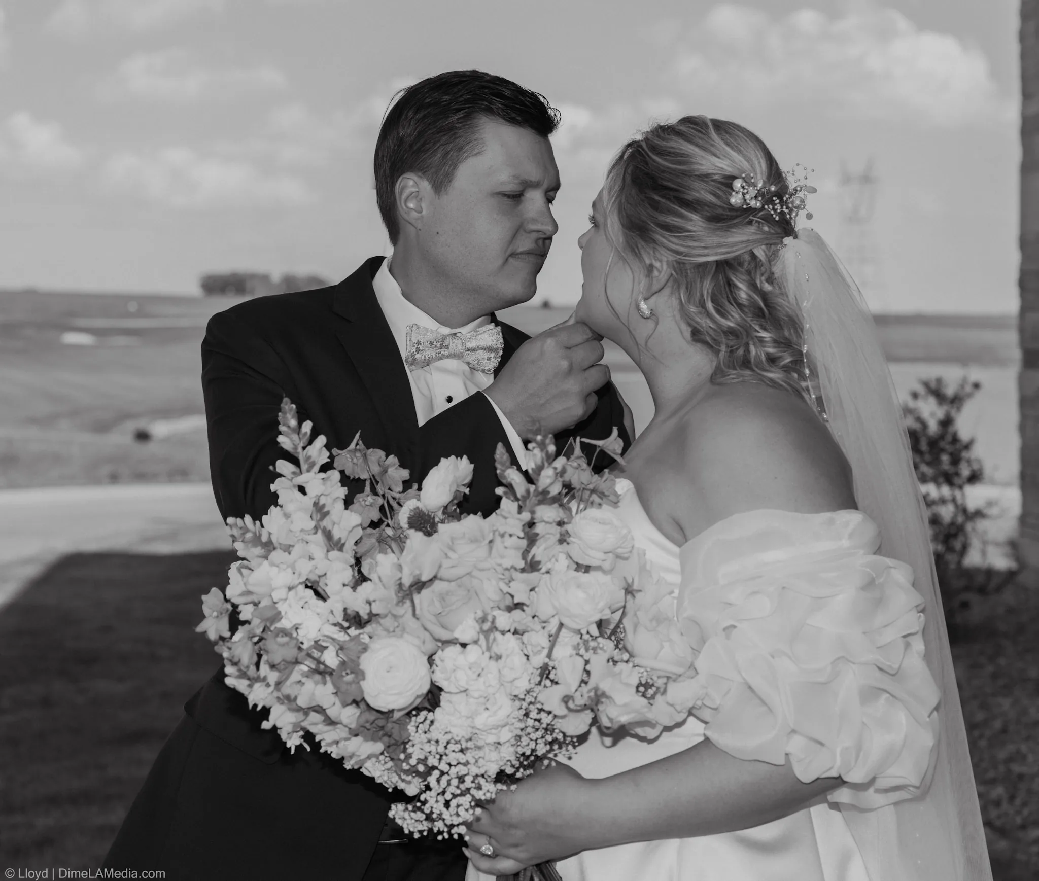 Bride and groom nose to nose over her bouquet, black and white wedding portrait