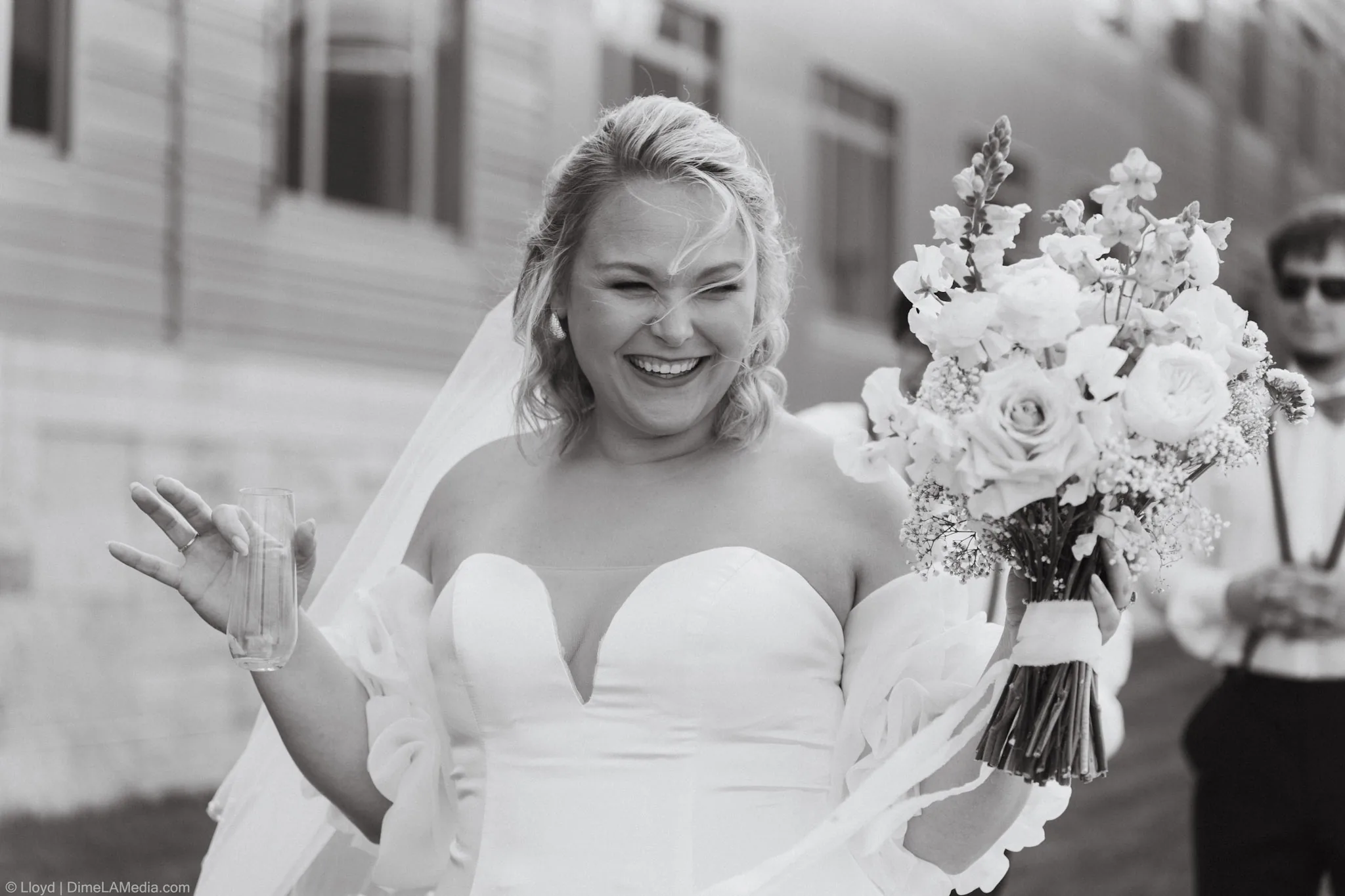 Bride laughing mid-toast with her bouquet, black and white