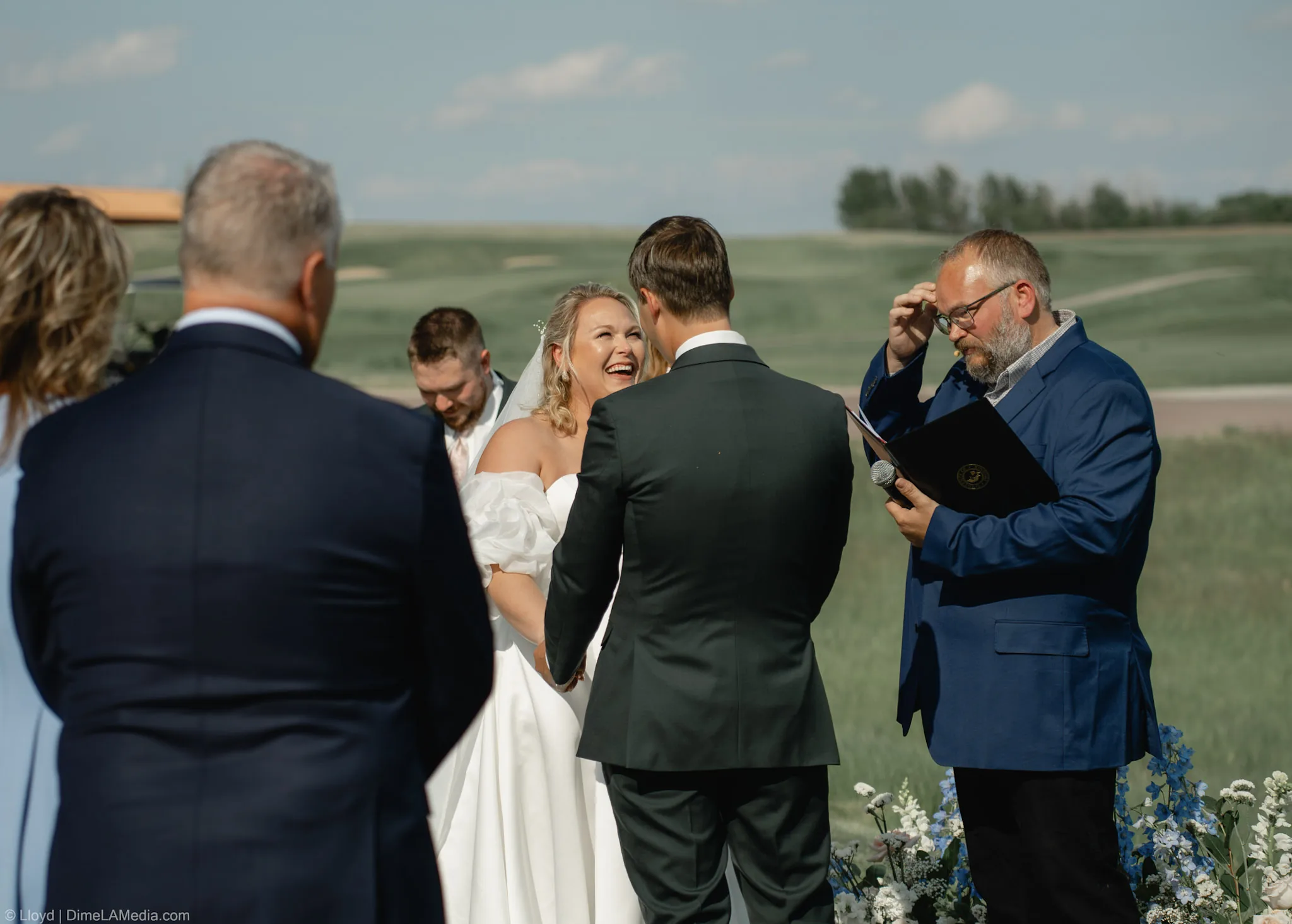 Bride and groom laughing at the altar as the officiant reads, outdoor South Dakota ceremony
