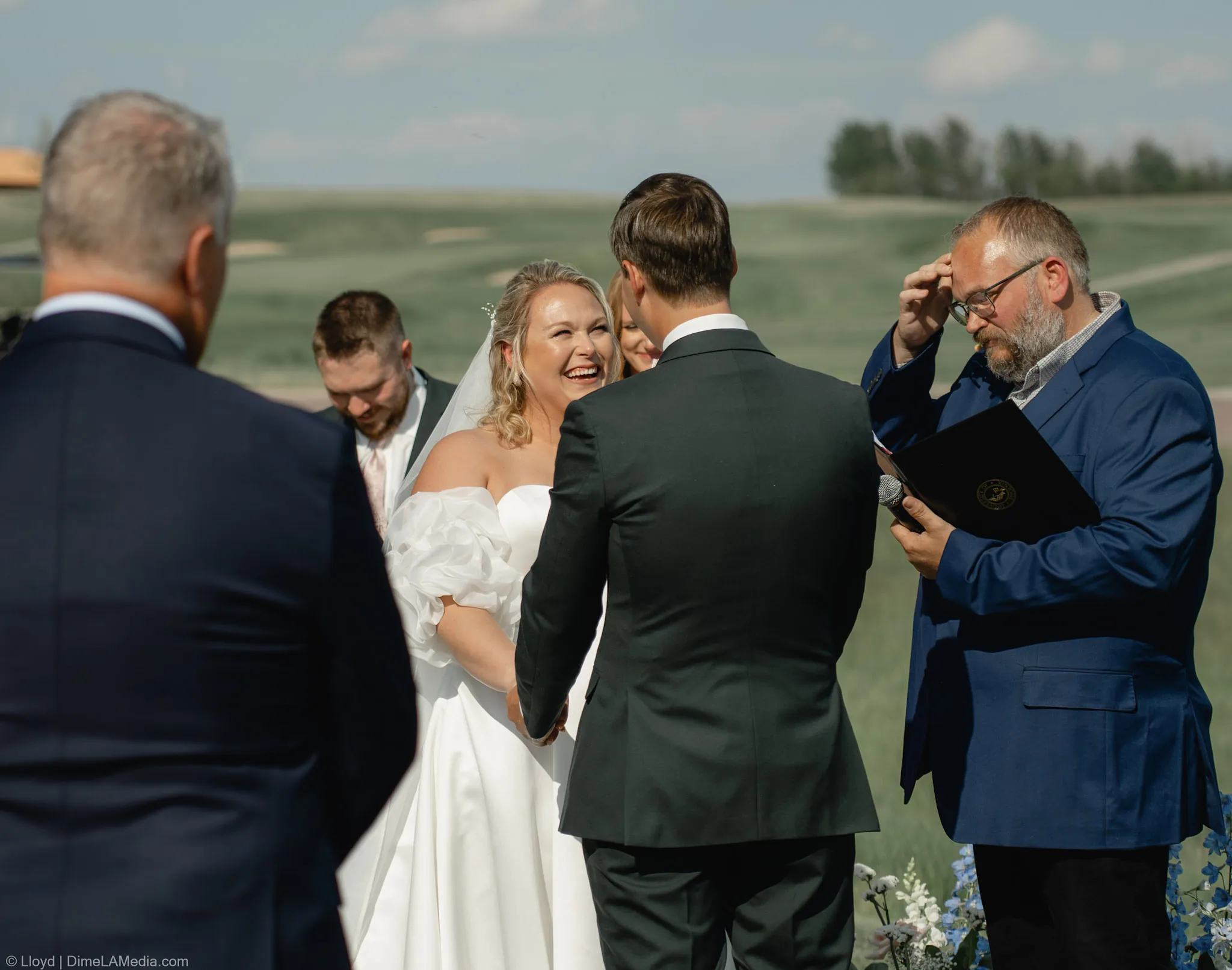 Bride laughing while holding her groom's hands during the ceremony