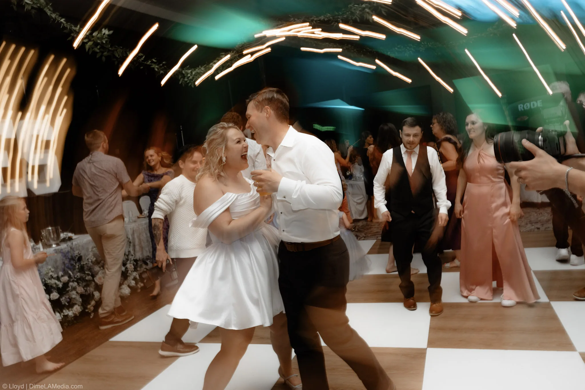 Bride and groom dancing together on the checkered floor as the light trails swirl around them
