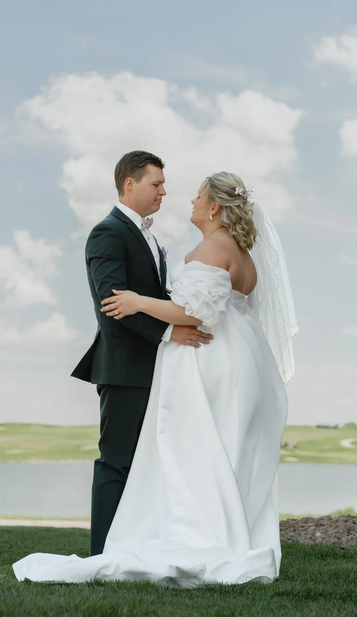 Bride and groom holding each other under towering prairie clouds after the first look, Sioux Falls SD